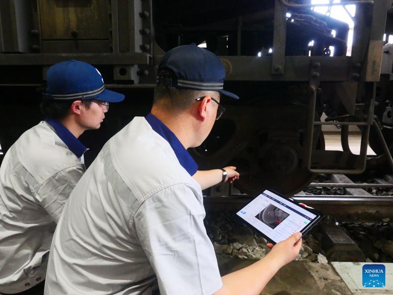 Wafanyakazi wakitumia kishikwambi kukagua sehemu ya hitilafu iliyoripotiwa na roboti ya teknolojia ya kisasa ya ukaguzi kwenye karakana ya matengenezo ya treni ya Kampuni ya Vifaa vya Reli ya China Energy katika Bandari ya Huanghua, Mkoa wa Hebei, Kaskazini mwa China, Mei 15, 2025. (Picha na Fu Xiuzhi/Xinhua)