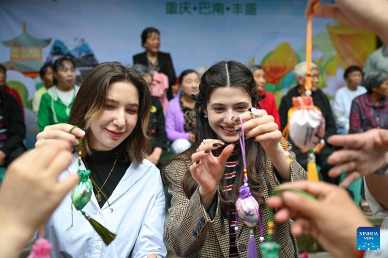 Wakazi wenyeji na wanafunzi wa kimataifa wakijaribu kutengeneza vifuko vya uturi katika mji wa kale wa Fengsheng wa  Eneo la Banan la Mji wa Chongqing, kusini-magharibi mwa China, Mei 28, 2025. (Xinhua/Chen Cheng)