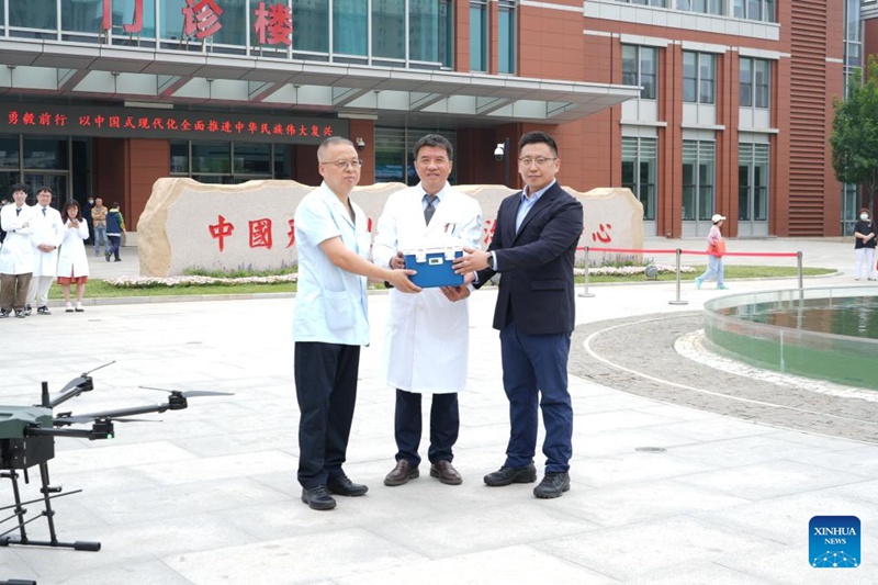 Shen Jun (katikati), makamu mkuu wa Taasisi ya Saratani na Hospitali ya Chuo Kikuu cha Tiba cha Tianjin, akipokea damu ya dharura iliyosambazwa na kuwasilishwa na droni wakati wa majaribio ya safari ya droni kwa kuigiza uhalisia katika tawi la hospitali hiyo la Binhai mjini Tianjin, kaskazini mwa China, Mei 21, 2025. (Xinhua)