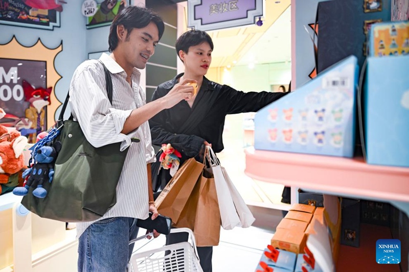 Watalii kutoka Thailand wakifahamishwa kuhusu bidhaa kwenye duka la midoli ya mitindo maarufu ya kisasa kwenye Mtaa wa Nanjing mjini Shanghai, mashariki mwa China, Julai 17, 2025. (Xinhua/Chen Haoming)