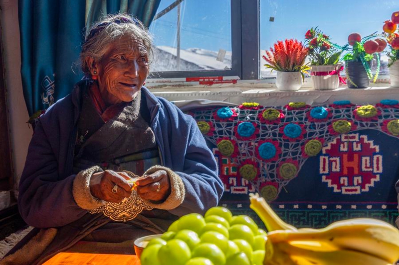 Mwanakijiji mzee akiwa ameketi kwenye nyumba yake mpya katika Kijiji cha Qaba cha Wilaya ya Dingri, Mji wa Xigaze, Mkoa Unaojiendesha wa Xizang, kusini magharibi mwa China, Novemba 13, 2025. (Xinhua/Jiang Fan)