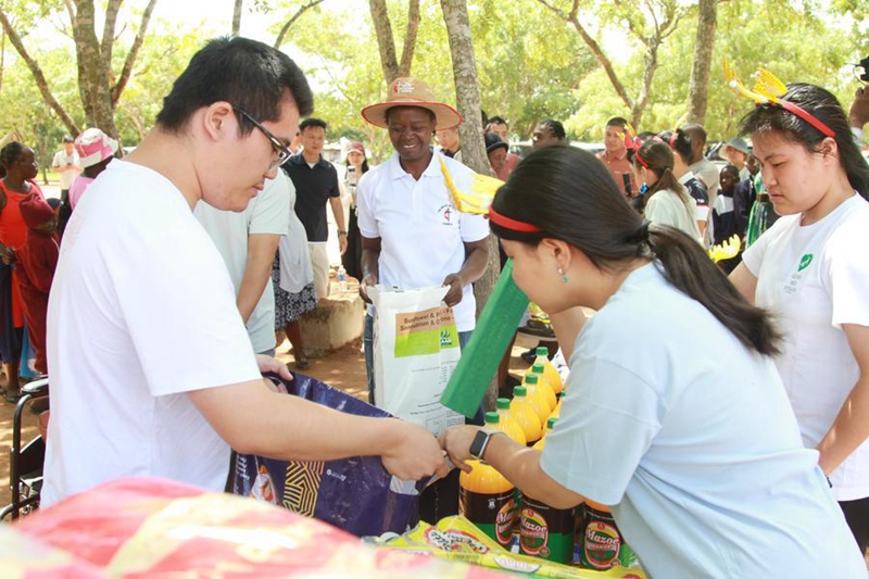 Wafanyakazi wa kujitolea kutoka Jumuiya ya Wafanyabiashara wa Hunan, China wanaofanya shughuli zao nchini Zimbabwe wakigawa mahitaji huko Epworth, Harare, Zimbabwe, tarehe 14 Desemba 2025. (Picha na Tafara Mugwara/Xinhua)