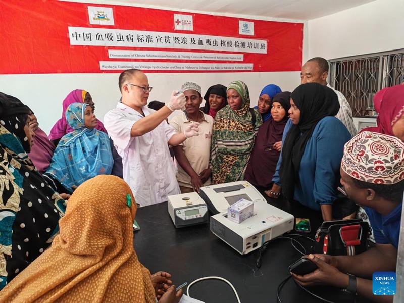 Mtaalamu wa afya kutoka China akionyesha  ufundi wa kuthibitisha ugonjwa wa kichocho kwa wataalamu wa afya wa Zanzibari kwenye warsha ya mafunzo visiwani Zanzibar, Tanzania, Oktoba 14, 2025. (Timu ya wataalamu wa China/kupitia Xinhua)