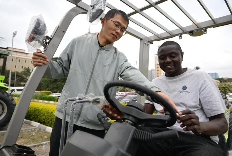 Muuzaji wa China (kushoto) akimsaidia mtembeleaji kuendesha forklift iliyotengenezwa China kwenye Maonyesho ya Kimataifa ya Mashine za Ujenzi ya Afrika 2026 jijini Nairobi, Kenya, Juni 19, 2026. (Xinhua/Yang Guang) 