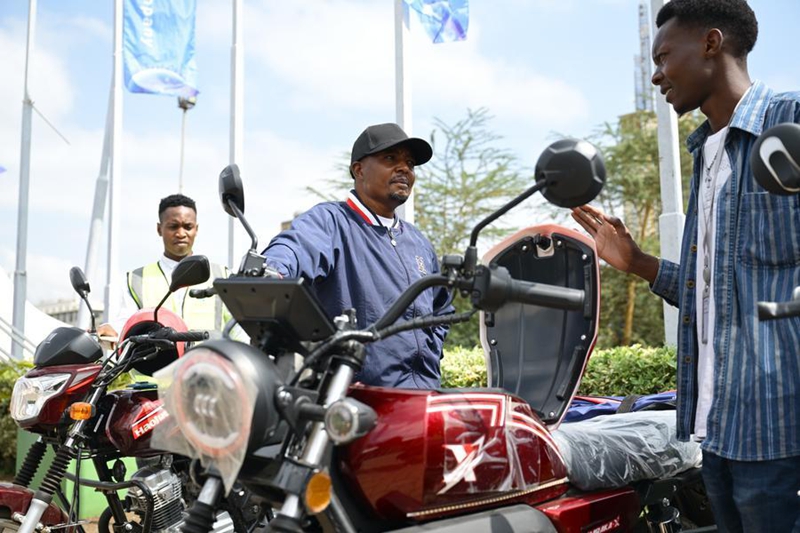 Wafanyakazi wa kampuni ya pikipiki za umeme wakipiga picha kwenye Maonyesho ya Kimataifa ya Mashine za Ujenzi ya Afrika 2026 jijini Nairobi, Kenya, Juni 19, 2026. (Xinhua/Yang Guang)