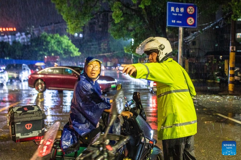 Ofisa wa polisi akimwelekeza mkazi mmoja kuchukua njia ya mkato katika Mji wa Ezhou, Mkoa wa Hubei, katikati mwa China, Julai 6, 2026. (Picha na Zhang Hongbin/Xinhua)