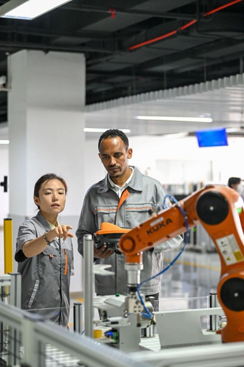 Tola Tsegaye Alemu (Kulia) kutoka Ethiopia akiendesha roboti ya viwandani chini ya mwongozo wa  mwalimu katika Chuo Kikuu cha Teknolojia na Elimu cha Tianjin kaskazini mwa China. Tianjin, Juni 27, 2024. (Xinhua/Sun Fanyue)